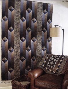 a brown leather chair sitting in front of a wall with a quilt hanging on it