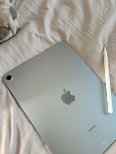 an apple laptop computer sitting on top of a bed next to a pen and mouse