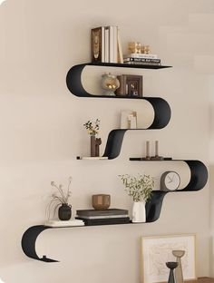 three shelves with books, vases and other items on them in the corner of a room