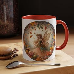 a red and white coffee mug sitting on top of a wooden table next to a spoon