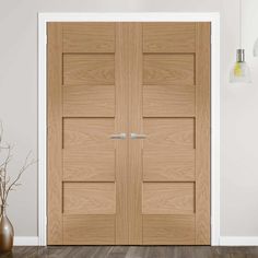 an empty room with two wooden doors and vases on the floor next to it