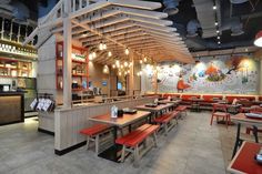 an empty restaurant with tables and red benches on the floor, lights hanging from the ceiling