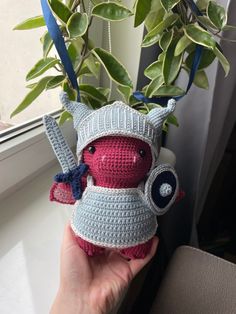 a crocheted stuffed animal is holding a plant