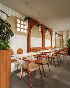 an empty restaurant with wooden chairs and plants