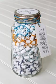 a jar filled with lots of white and blue spools next to a tag