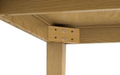 a close up view of the corner of a wooden table with two holes in it