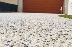 a close up view of a driveway with gravel and rocks in front of a garage door