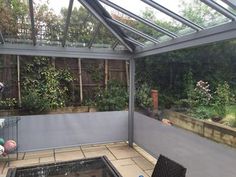 an enclosed patio with tables and chairs in the back ground, surrounded by greenery