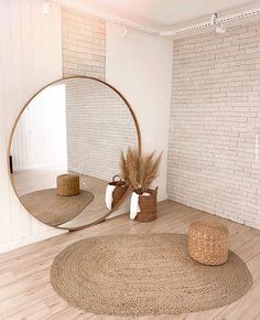 a round mirror sitting on top of a wooden floor next to two baskets filled with plants