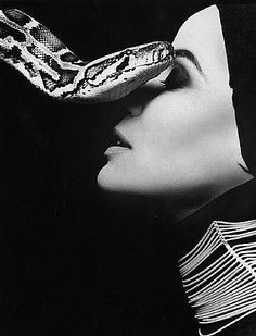 a woman with a snake on her head in front of her face, black and white photo