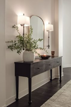 a table with a mirror and vase on it next to a wall mounted candle holder