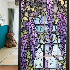 a stained glass window with purple flowers on it and a teddy bear in the background