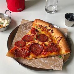 a slice of pepperoni pizza sitting on top of a plate next to a bowl of potato salad