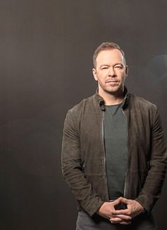 a man standing in front of a black background with his hands on his hips and looking at the camera