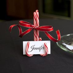 two candy canes tied to a table with a name tag on it and a glass plate