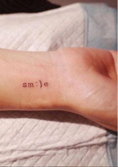 a person with a small tattoo on their arm that says smile and the word smile is written in red ink