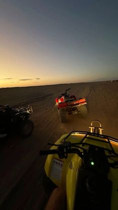 two atvs driving on the beach at sunset with one being pulled by an atv