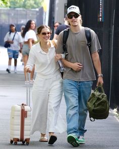 a man and woman walking down the street with luggage