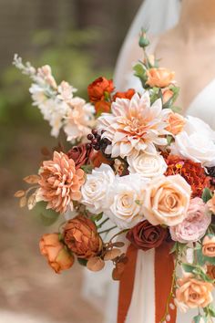 a bridal holding a bouquet of flowers in it's hands and wearing an orange ribbon