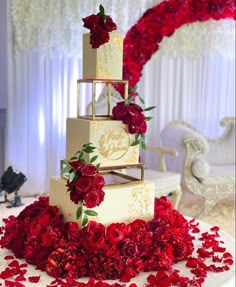 a three tiered wedding cake with red flowers on the bottom and gold trimmings