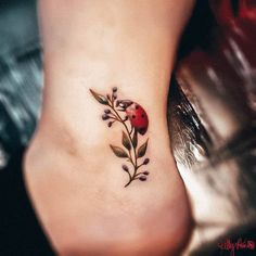 a ladybug tattoo on the side of a woman's foot with leaves