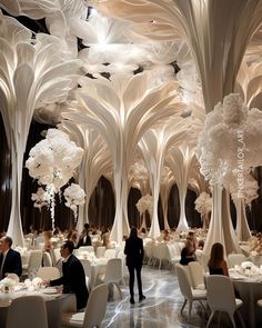 people are sitting at tables in the middle of a room with tall white trees on it