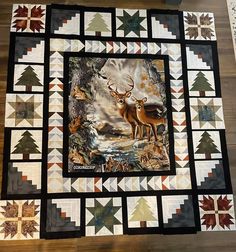 a quilted wall hanging on the floor with deers and trees in it's center