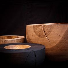 two wooden bowls sitting next to each other on top of a black surface with holes in it