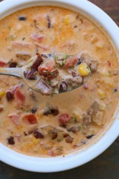 a white bowl filled with soup sitting on top of a wooden table next to a spoon