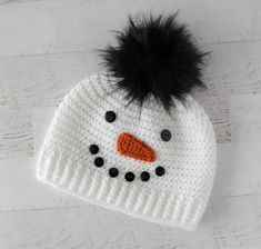 a crocheted snowman hat with a black pom - pom