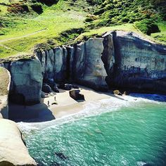 an aerial view of the beach and cliffs in the ocean with people walking on it