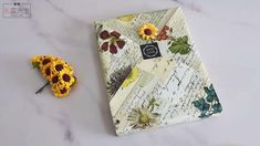 an open book with flowers on it next to a pair of dried sunflowers