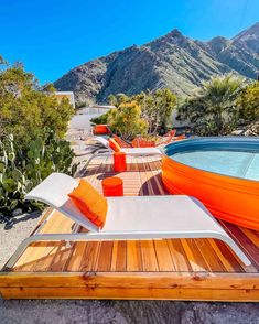 an outdoor hot tub and lounge chairs with mountains in the background