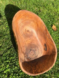 a wooden bowl sitting on top of green grass