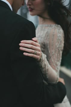 a man and woman standing next to each other with their arms around each other's shoulders