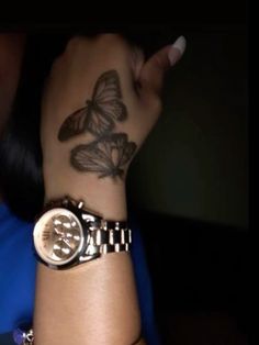 a woman's wrist with a butterfly tattoo on it and a watch in the foreground