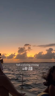 two people sitting on a boat watching the sun go down over the ocean and clouds