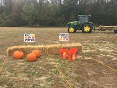 hay bales and pumpkins are set up on the ground in front of a tractor