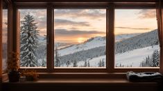 a window with a view of snow covered mountains and pine trees in the foreground