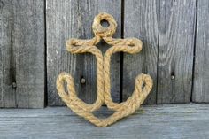 an anchor is hanging on the side of a wooden wall with rope attached to it