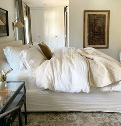 a bed with white sheets and pillows in a room