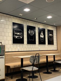 three black and white pictures hang on the wall above tables in a fast food restaurant