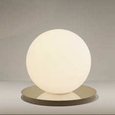 a white ball sitting on top of a metal stand next to a gray wall and floor