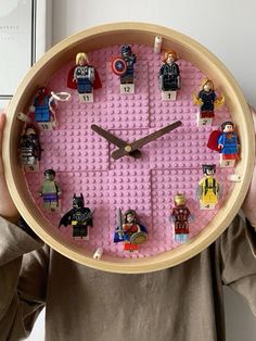 a person holding up a clock made out of legos