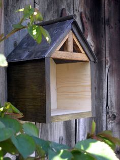 a bird house hanging on the side of a wooden fence