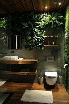 a bathroom with plants growing on the wall and toilet in the center, along with wooden flooring