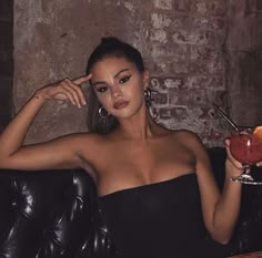 a woman sitting in a chair holding an apple and looking at the camera with one hand on her head