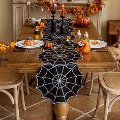 a dining room table decorated for halloween with pumpkins and spider web decorations on it