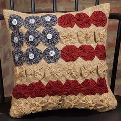 an american flag pillow with red, white and blue bows on it sitting on a chair