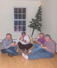 four men sitting on the floor eating food